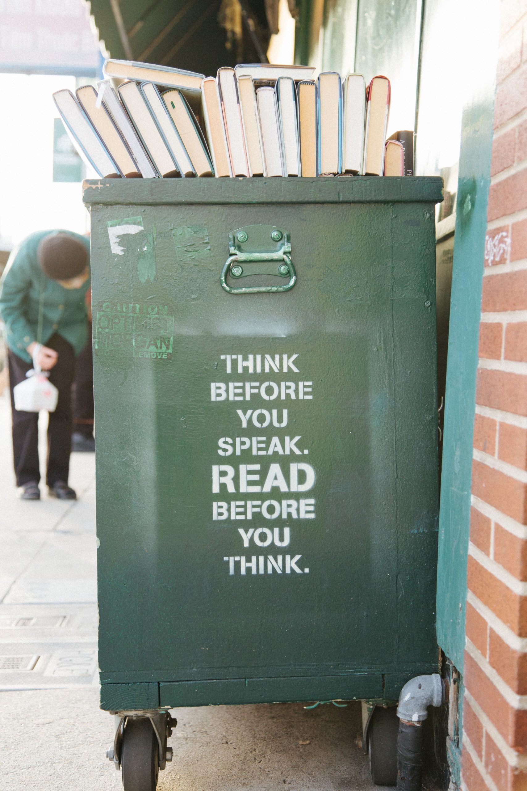 A green bookshelf on wheels with the following text painted on the side in capital letters: "Think before you speak. Read Before you think."