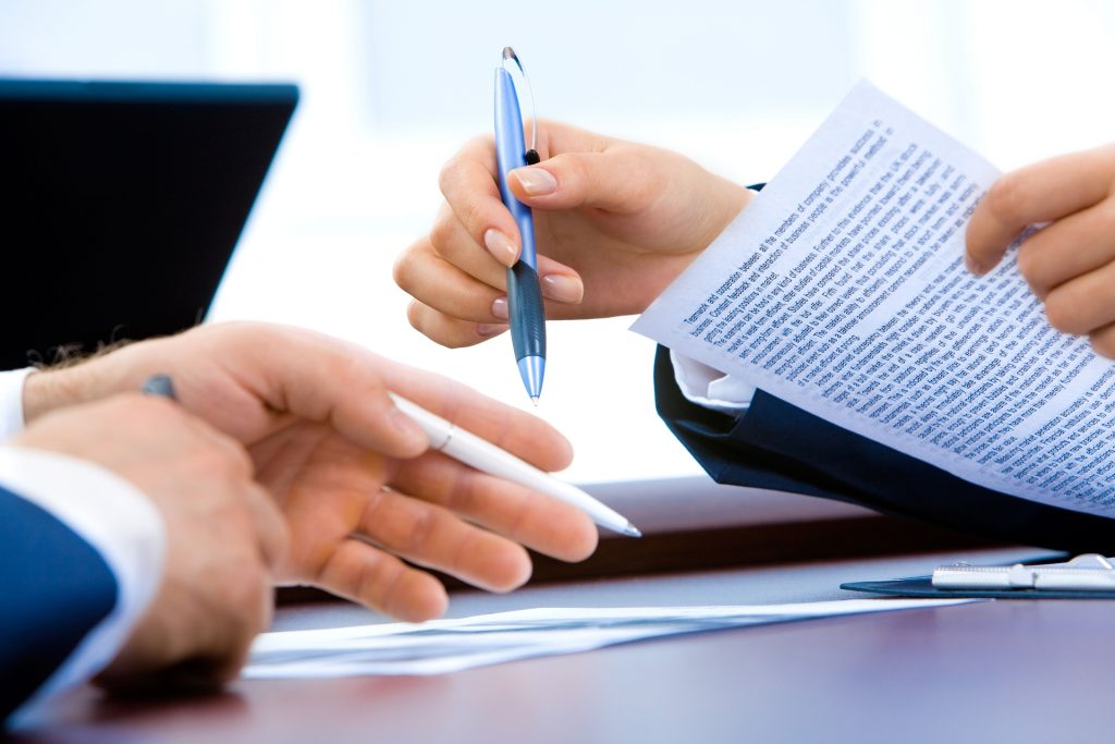 Hands holding a paper and pens.