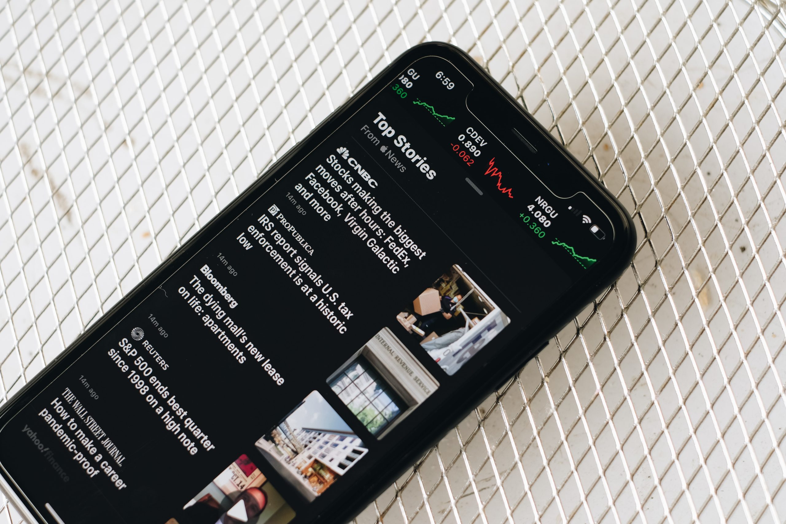 A black smartphone displays the top stories from the News app.