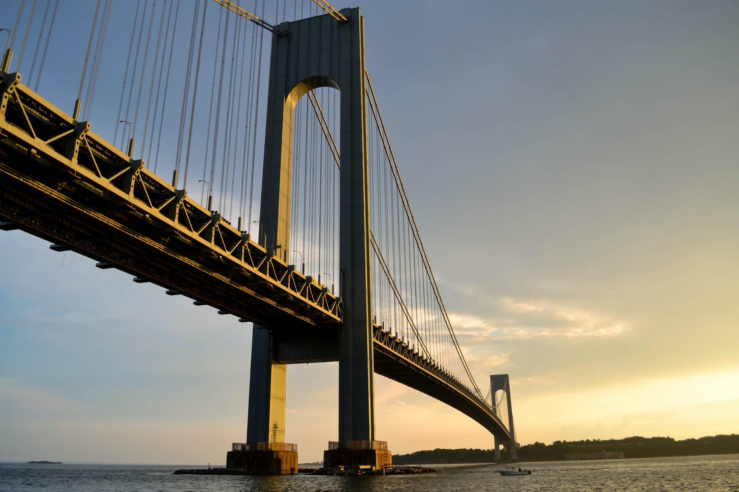 A gray metal suspension bridge across a body of water.