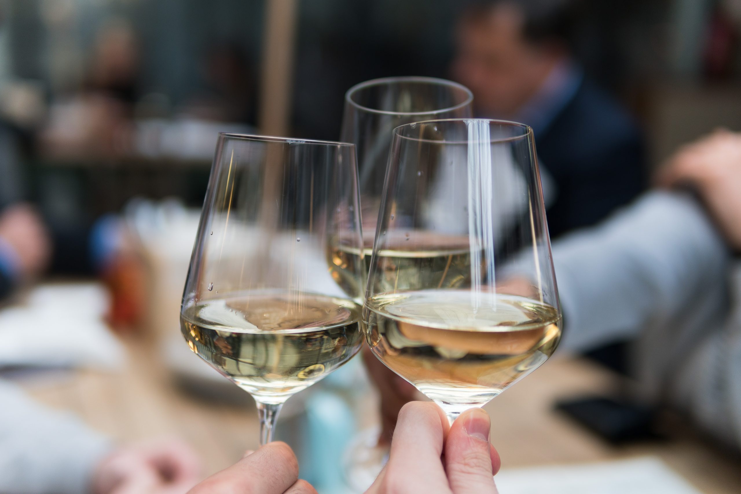 Three people having a wine toast using clear crystal wine glasses.