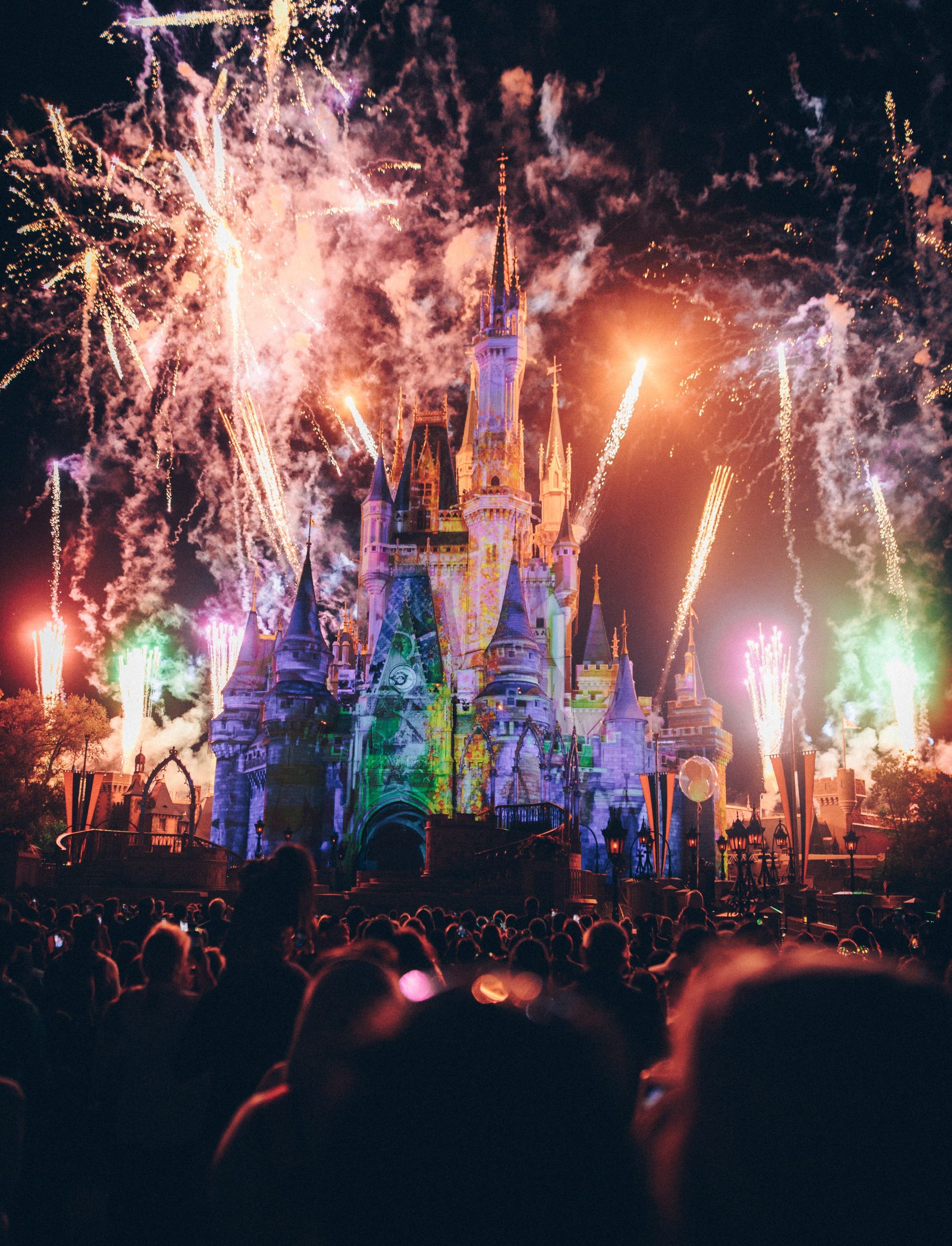 Fireworks display at DisneyLand with a lot of people watching in front of the castle.