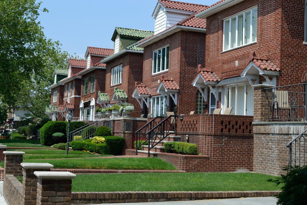 A row of brick town houses with green lawns.