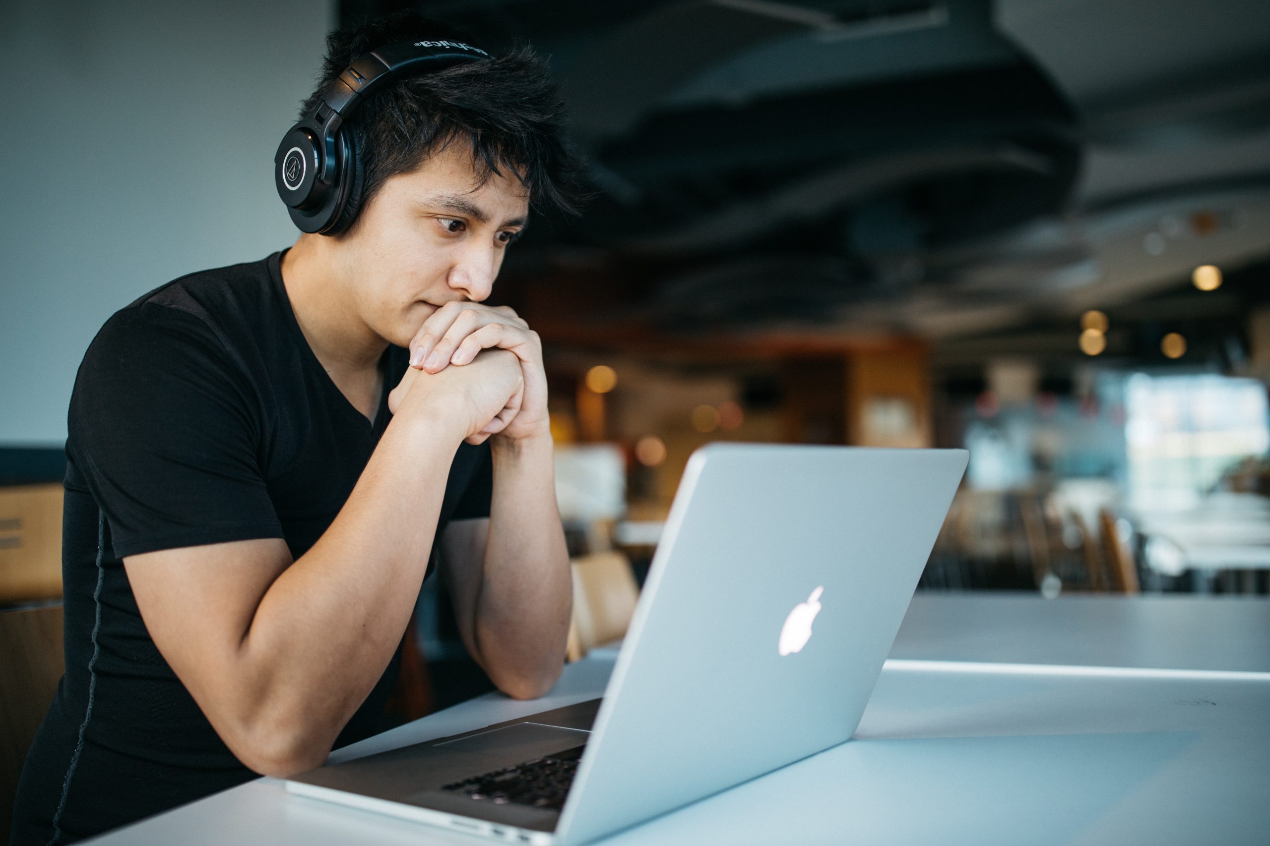 A student with headphones in front of the laptop.
