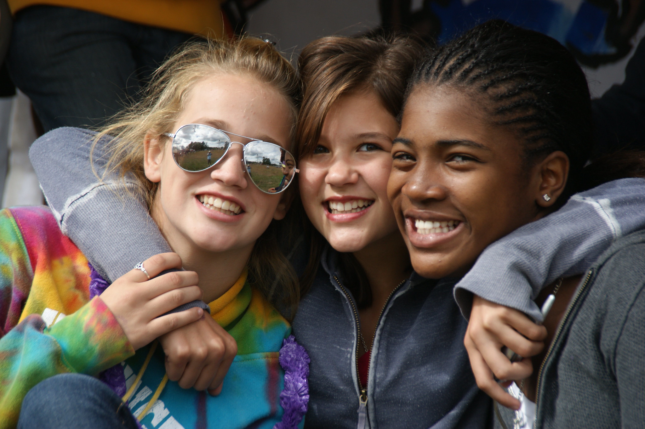 three teenage girls smiling and hugging