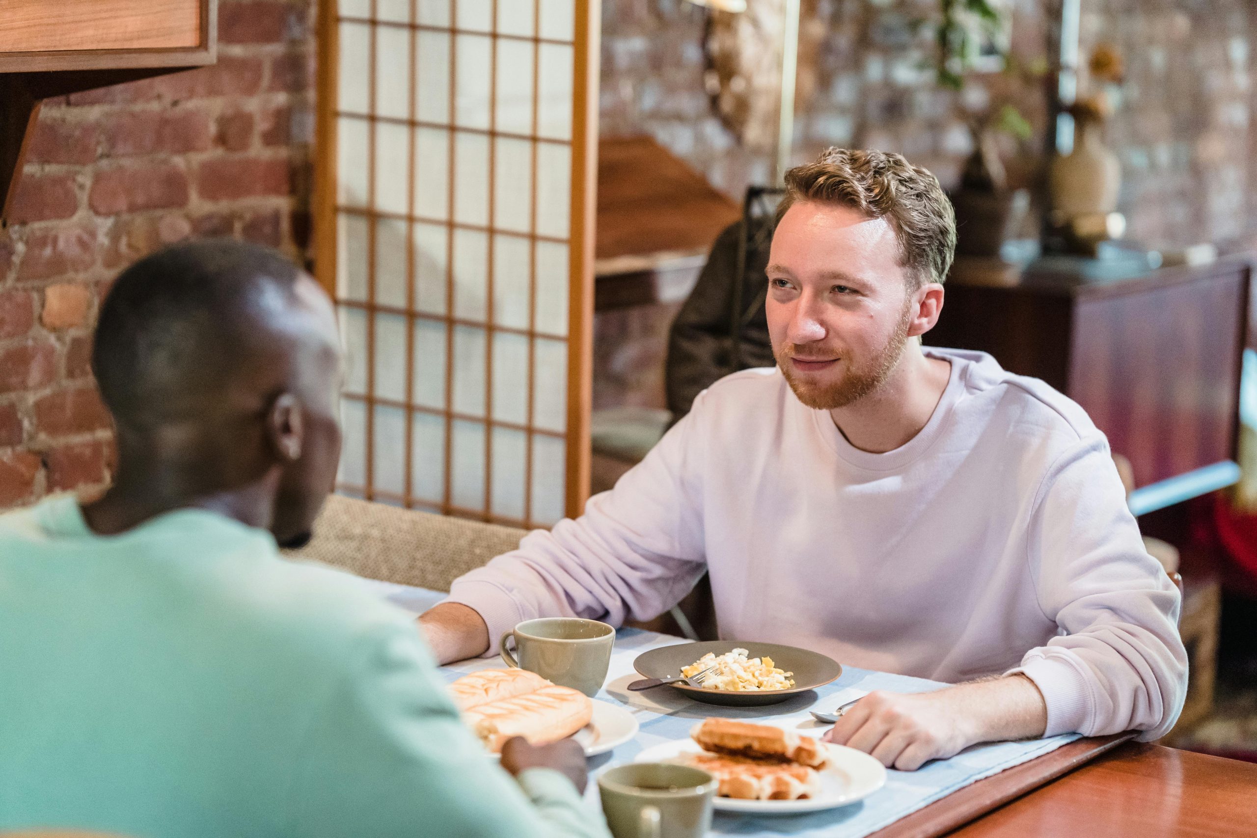 A photograph shows two people making eye contact during a conversation over breakfast.