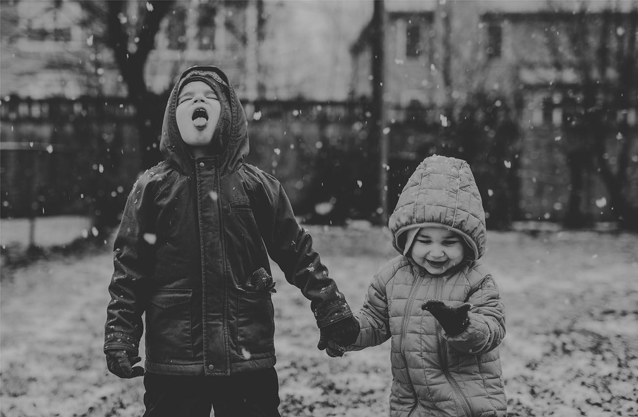 A photograph shows two children running outside through an open doorway in the snow.