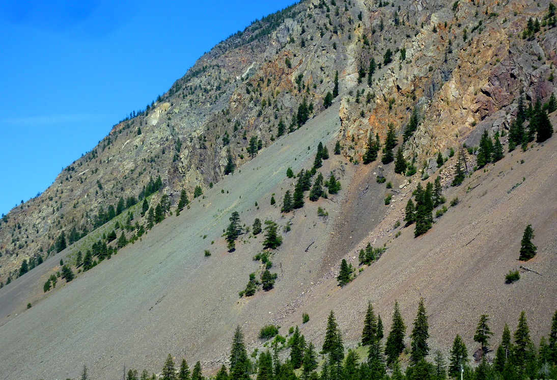 Photograph of an area with very effective frost-wedging near to Keremeos, BC. The fragments that have been wedged away from the cliffs above have accumulated in a talus deposit at the base of the slope. The rocks in this area have quite varied colours, and those are reflected in the colours of the talus.