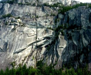 Figure 3.21 The Stawamus Chief, part of the Coast Range Plutonic Complex, near to Squamish, B.C. The cliff is about 600 m high. Most of the dark stripes are a result of algae and lichen growth where the surface is frequently wet, but there is a large (about 10 m across) vertical dyke that extends from bottom to top. [SE photo]